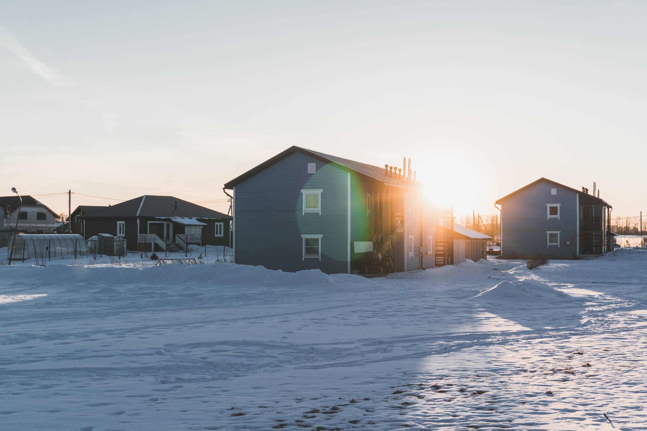 Omakotitaloja talvisessa auringonlaskussa